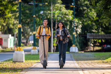 Two women riding scooters down a sidewalk