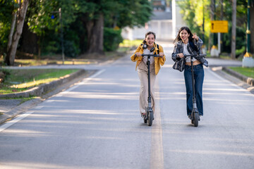 Two women riding scooters down a street