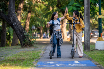 Two women on scooters are high fiving each other