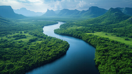 Aerial shot of a winding river cutting through lush green valleys, reflecting the blue sky above
