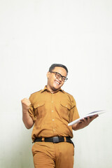 Indonesian Middle School Teacher is excited. The teacher is wearing old khaki and carrying a book