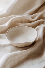 A delicate, textured bowl resting on soft, neutral fabric.