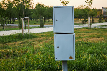 Small outdoor electrical enclosure, distribution cabinet on pole in city park. Two metal box gray color at street