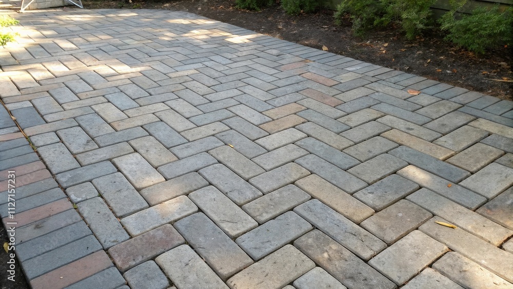 Poster a herringbone pattern of gray, tan, and red bricks creates a walkway lined with lush greenery.