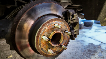 Close-up of a rusty car brake disc in a garage, highlighting vehicle maintenance issues and repair...