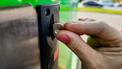 A person inserting a coin into a machine slot, illustrating the concept of public transportation payment and urban commuting