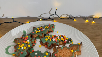 Festive Christmas-themed cookies decorated with colored sprinkles sit on a white plate, capturing the essence of holiday baking