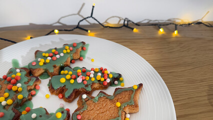 Festive Christmas tree-shaped cookies decorated with green icing and colorful sprinkles on a plate, perfect for holiday celebrations