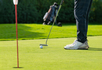 Golfer putting ball on green during sunny day