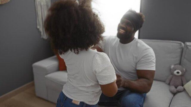 Father enjoying playful moment with daughter in cozy living room, embracing family love, happiness, and togetherness in a warm home setting