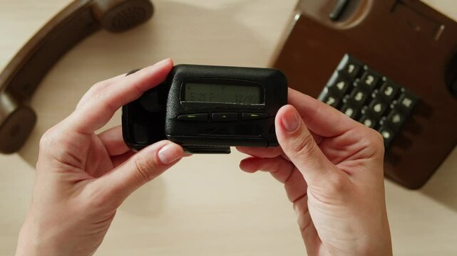 Pager beeper device close up on a desk, retro phone 90s instant communication and connection, sms messaging in the early 80s 90s digital age