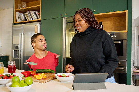 Smiling woman and man with phocomelia in kitchen