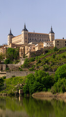 Obraz premium Vertical view of the Alcázar of Toledo with its surrounding hillside and river