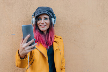 urban young woman with headphones and mobile phone in the street with yellow jacket