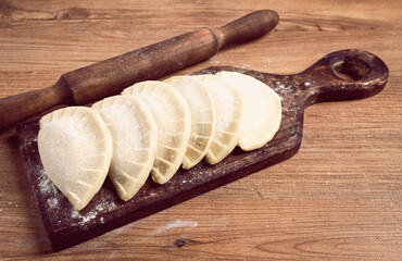 raw chebureks, mini, on a cutting board, wooden table, close-up, no people,