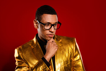 Stylish young man in a gold glossy suit posing against a vibrant red backdrop, showcasing charisma...