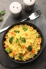 Tasty rice with vegetables served on grey table, top view