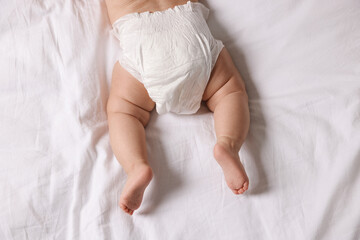 Cute little baby in diaper on bed, top view