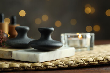 Spa stones and burning candle on table, closeup