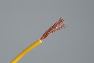 Yellow stripped electrical wire on light grey background, closeup