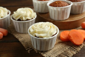 Tasty carrot muffins and fresh vegetable on wooden table, closeup
