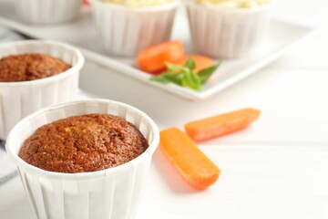 Tasty carrot muffins and fresh vegetables on white wooden table, closeup. Space for text