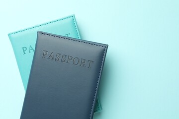 Passports in color covers on light blue background, top view. Space for text