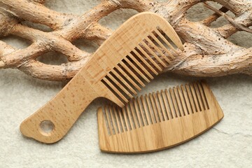 Wooden hair combs and tree branch on beige background, closeup