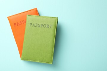 Passports in color covers on light blue background, top view. Space for text