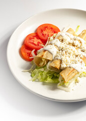 Tacos dorados en aceite en plato blanco