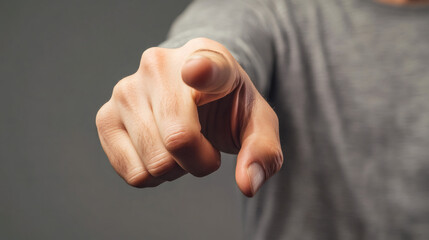 Man pointing his index finger accusingly at the viewer with a gray background in close-up shot