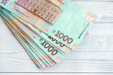 Big amount of ukrainian new one hundred hryvnia money bills with modern design on white wooden table. Financial concept, business