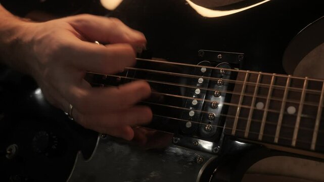 guitarist plays electric guitar. pick on guitar strings close-up