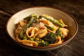 a bowl of pasta cappelletti mixed with green vegetables such as broccoli and green beans, stewed in a gravy