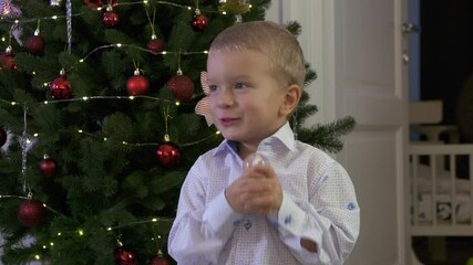 Happy child holding snow globe with figurine of Santa Claus. Smiling face of little boy near Christmas tree. Merry Christmas and Happy New year winter holidays.