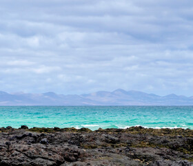 Black lava formations on the coast of the Atlantic ocean with a clean blue water.