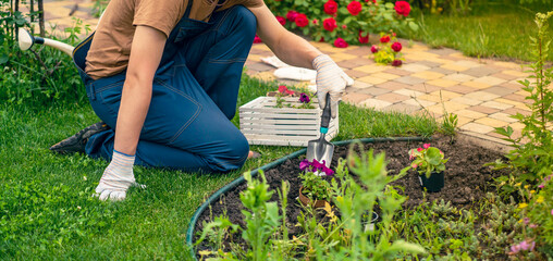 A young man in a straw hat and hands in gloves is engaged in gardening work