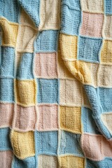 A cozy knitted blanket featuring a pastel color grid pattern.