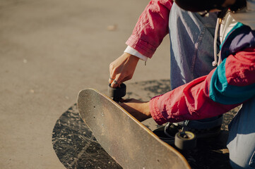 Obraz premium Skater fixing wheels on skateboard in skatepark