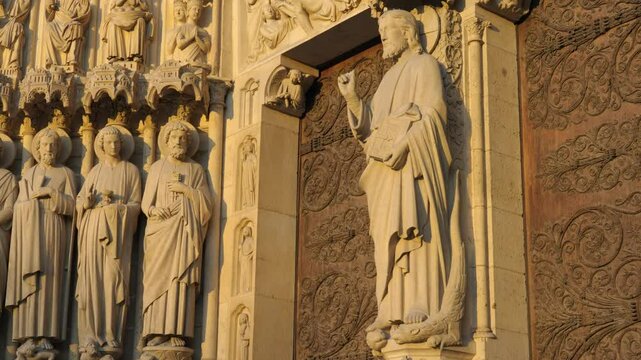 Intricate stone carvings of saints on the facade of Notre Dame Cathedral in Paris, showcasing Gothic architecture and religious art