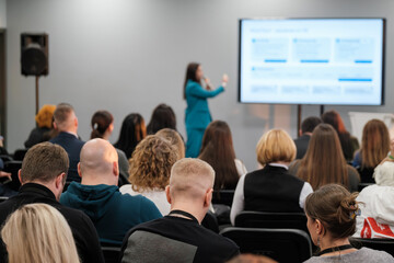 Audience engaged during a presentation with speaker using a microphone and a screen.