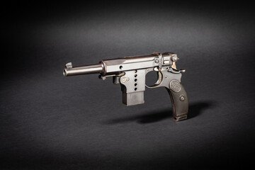 Studioaufnahme einer Bergmann Mod. 1897 No. 5 historischen Pistole Kurzwaffe auf schwarzem Untergrund mit Schlagschatten dramatischen Licht