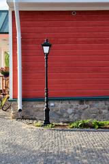 A beautiful bronze lantern stands on the corner of a wooden house against the background of a wall