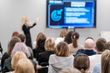 Audience focused on presentation during business conference. Engaged crowd watching speaker deliver talk at event.