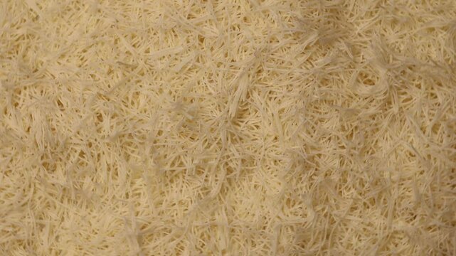 Kataifi dough rotating in a circle. Shredded phyllo dough turning, showing its fine, delicate strands. Raw dough used for preparing Dubai chocolate desserts and Middle Eastern sweets.  