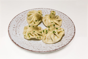 Boiled khinkali on white-brown dish on white table