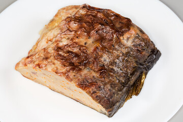 Piece of stuffed fish carp on white dish close-up
