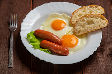 Breakfast fried eggs with sausages, crispy white bread and greens, and tea on the table