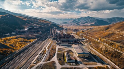Fototapeta premium Aerial panorama of a thermal power plant surrounded by mountains and industrial landscape during a scenic cloudy day.