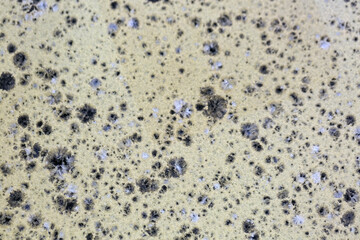 Close up of frying pan the yellowish surface, texture background. Clusters of black and gray patches are visible. Cast iron macro backgrounds. Closeup textured yellow stone surface with abstract feel